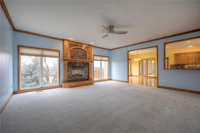 unfurnished living room featuring ornamental molding, light colored carpet, a large fireplace, and ceiling fan