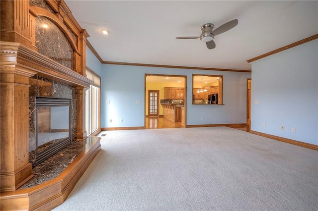 unfurnished living room with ornamental molding, light colored carpet, ceiling fan, and a high end fireplace