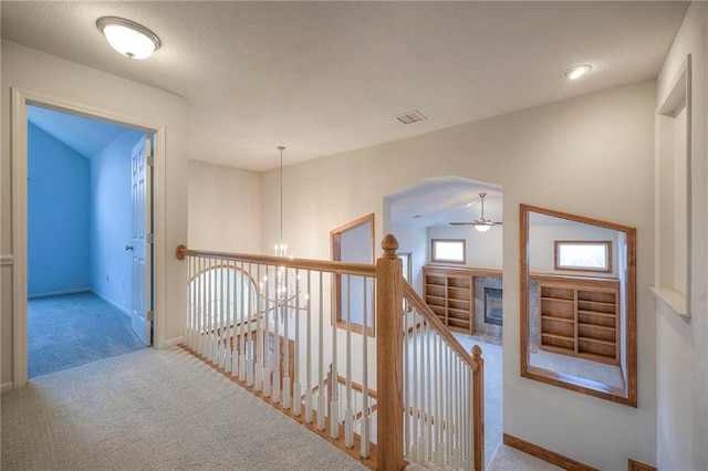 hall with light colored carpet and a notable chandelier