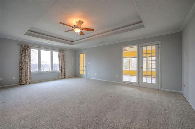 carpeted empty room with crown molding, a raised ceiling, and ceiling fan