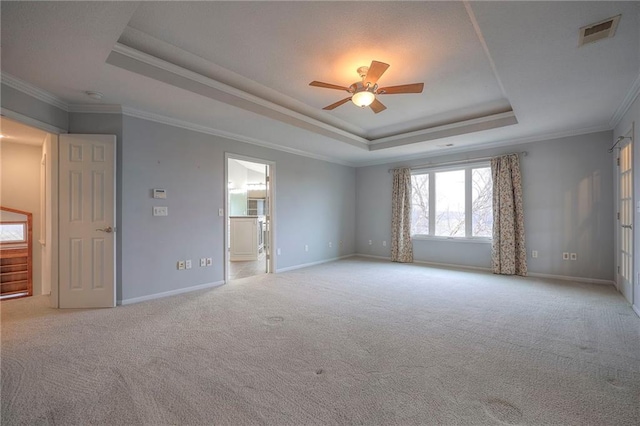 carpeted empty room featuring crown molding, ceiling fan, and a raised ceiling