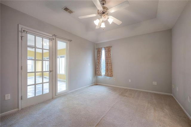 carpeted empty room featuring a tray ceiling and ceiling fan