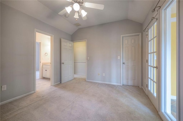 unfurnished bedroom featuring ceiling fan, light colored carpet, lofted ceiling, and connected bathroom