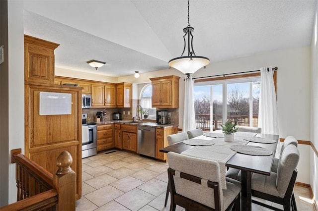 kitchen featuring sink, vaulted ceiling, hanging light fixtures, appliances with stainless steel finishes, and backsplash