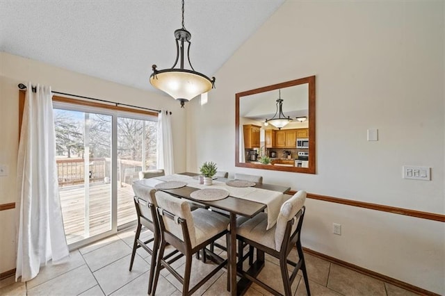 tiled dining space with vaulted ceiling and a textured ceiling