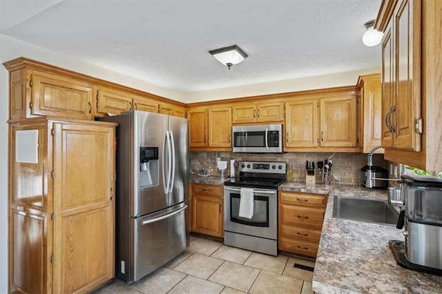 kitchen featuring tasteful backsplash, sink, light tile patterned floors, and appliances with stainless steel finishes