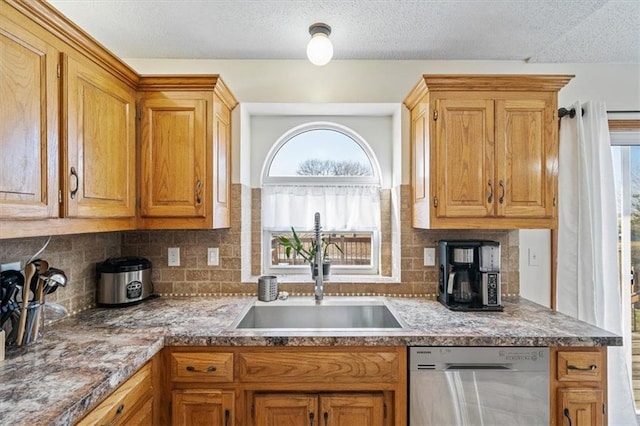 kitchen featuring sink, stainless steel dishwasher, backsplash, and a textured ceiling