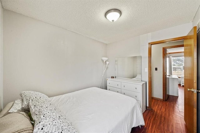 bedroom with dark hardwood / wood-style floors and a textured ceiling