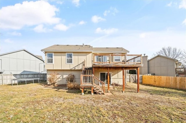 back of property with a trampoline, a yard, and a deck