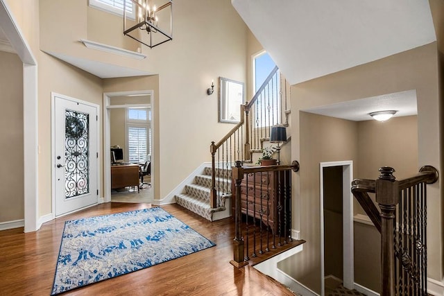 foyer with a high ceiling, wood-type flooring, and an inviting chandelier