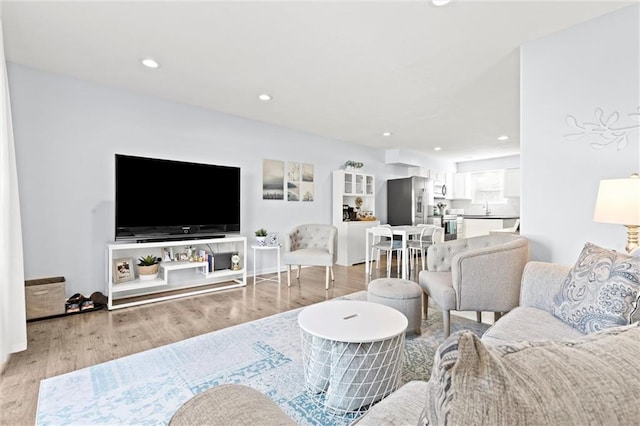 living room featuring sink and light hardwood / wood-style flooring