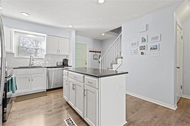 kitchen featuring white cabinetry, dishwasher, a kitchen island, and tasteful backsplash