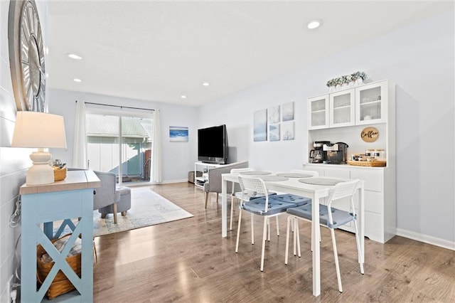 dining room featuring baseboards, wood finished floors, and recessed lighting