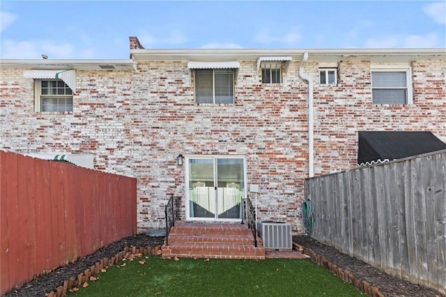 back of house with entry steps, fence, central AC, and brick siding