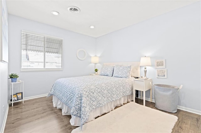 bedroom with recessed lighting, wood finished floors, visible vents, and baseboards