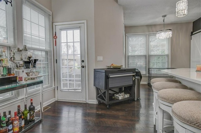 entryway with dark hardwood / wood-style floors, a barn door, an inviting chandelier, and a textured ceiling