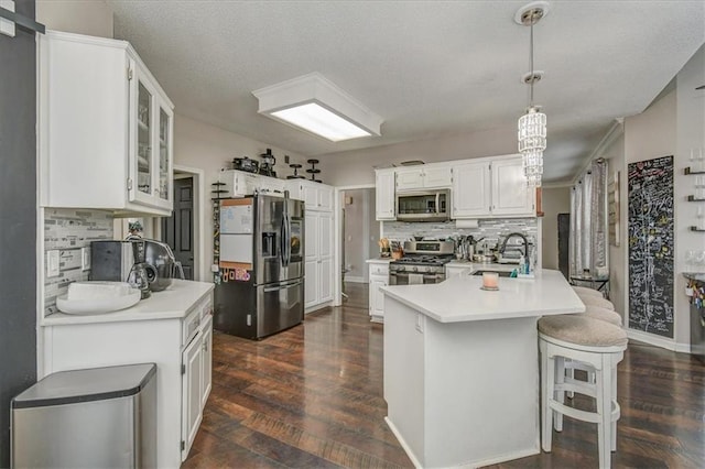 kitchen with stainless steel appliances, sink, pendant lighting, and white cabinets