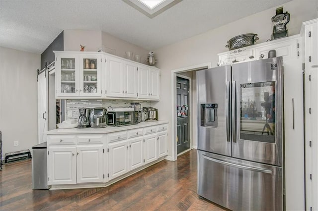 kitchen with dark wood-type flooring, stainless steel fridge, and white cabinets