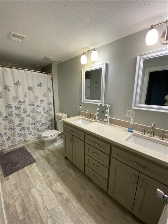 bathroom featuring vanity, hardwood / wood-style flooring, toilet, and a textured ceiling