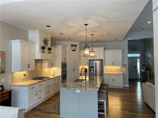 kitchen featuring an island with sink, appliances with stainless steel finishes, sink, and white cabinets