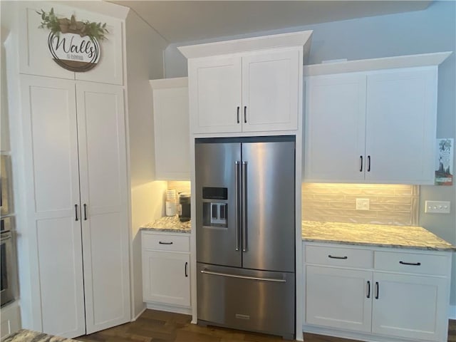 kitchen with stainless steel appliances, light stone countertops, and white cabinets