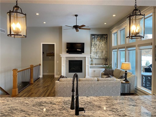 living room featuring ceiling fan with notable chandelier, plenty of natural light, and dark hardwood / wood-style floors