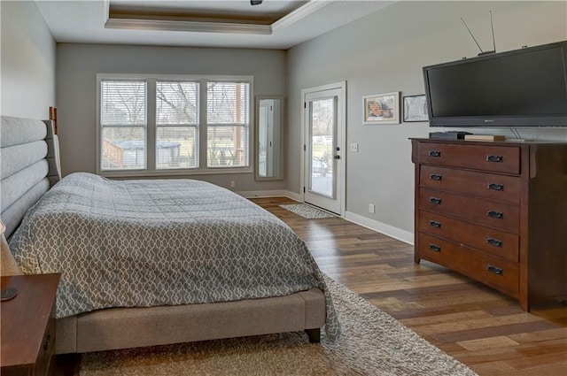 bedroom with a tray ceiling, hardwood / wood-style floors, and access to outside