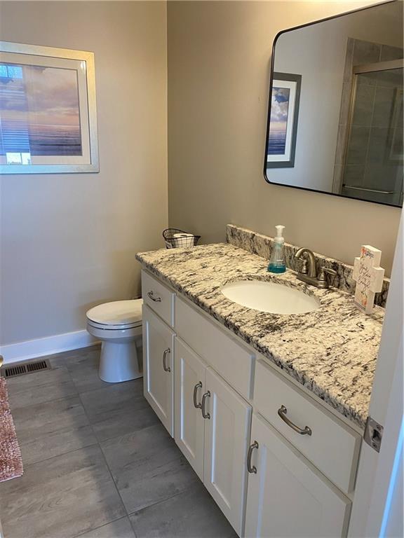 bathroom featuring vanity, toilet, and a shower with door