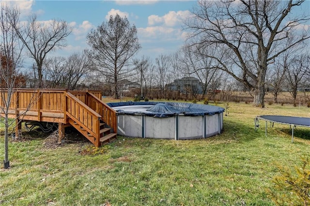 view of pool with a wooden deck, a yard, and a trampoline