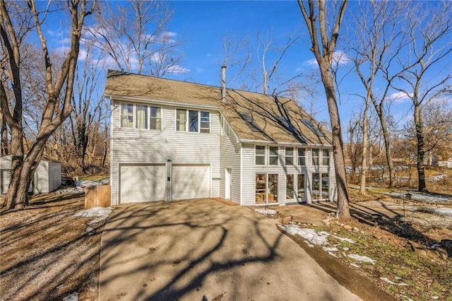 view of front facade featuring aphalt driveway, an attached garage, and a sunroom