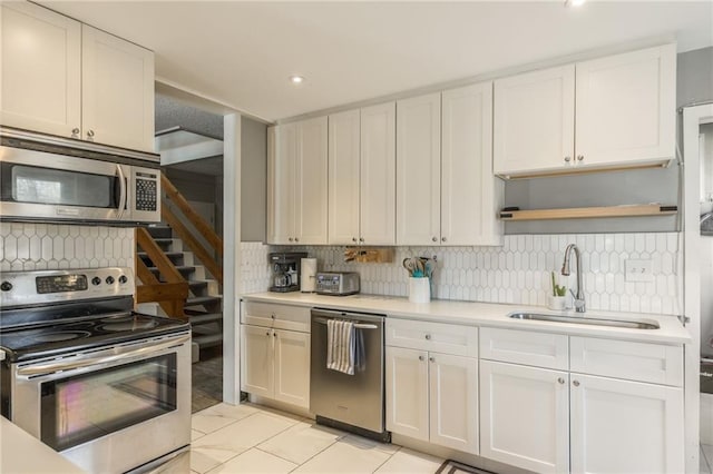 kitchen featuring stainless steel appliances, a sink, light countertops, and white cabinetry