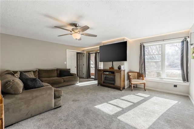 living room with carpet floors, ceiling fan, baseboards, and a textured ceiling