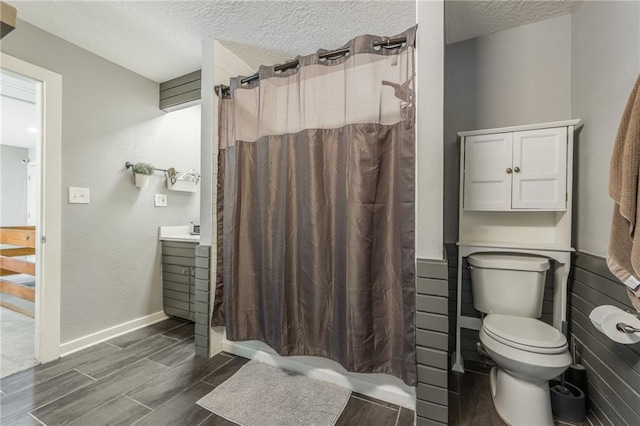 full bath featuring toilet, wood tiled floor, vanity, a textured ceiling, and a shower with curtain