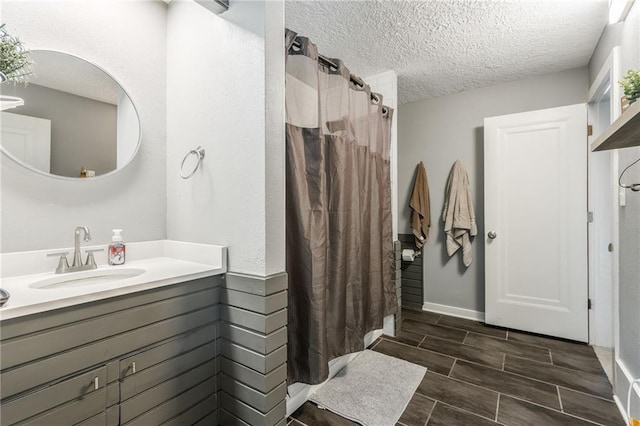 full bath featuring a shower with curtain, wood tiled floor, a textured ceiling, and vanity