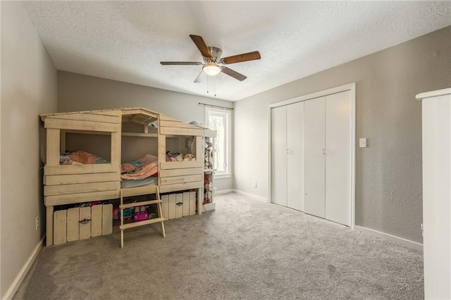 carpeted bedroom featuring a textured ceiling, a closet, a ceiling fan, and baseboards