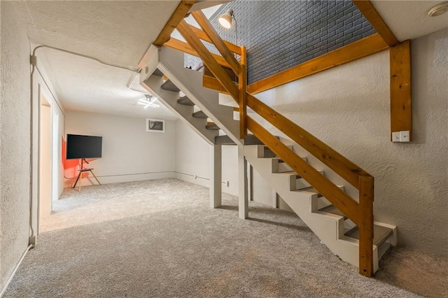 basement with stairs, a textured wall, and carpet