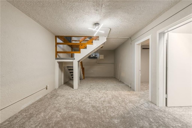 finished below grade area featuring a textured ceiling, a textured wall, stairway, and light colored carpet