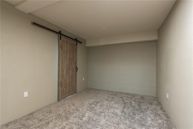 carpeted empty room with a barn door