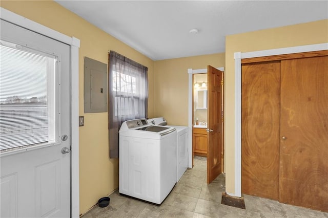 clothes washing area with sink, electric panel, and washer and clothes dryer