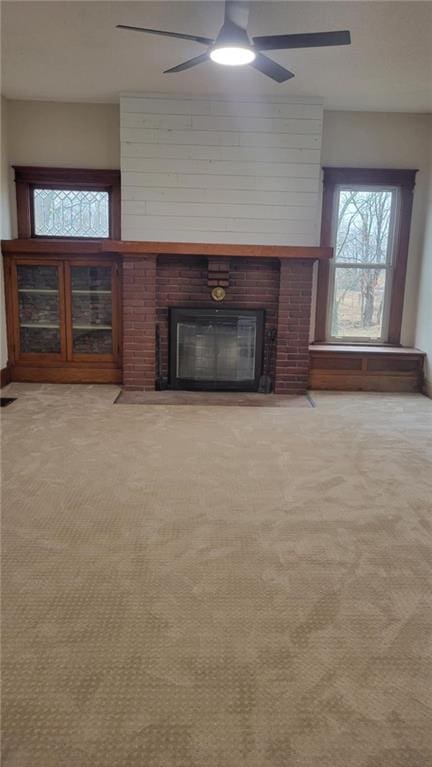 unfurnished living room with ceiling fan, light carpet, and a brick fireplace