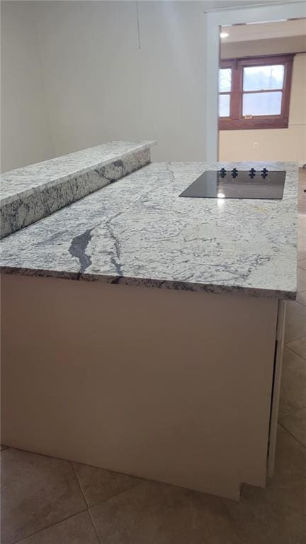 kitchen with black electric cooktop, tile patterned flooring, and light stone counters