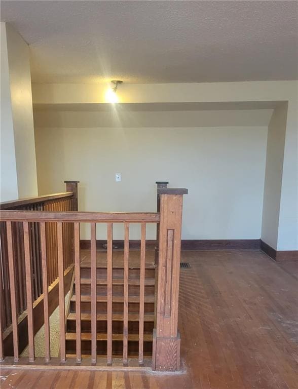 stairs with hardwood / wood-style floors and a textured ceiling