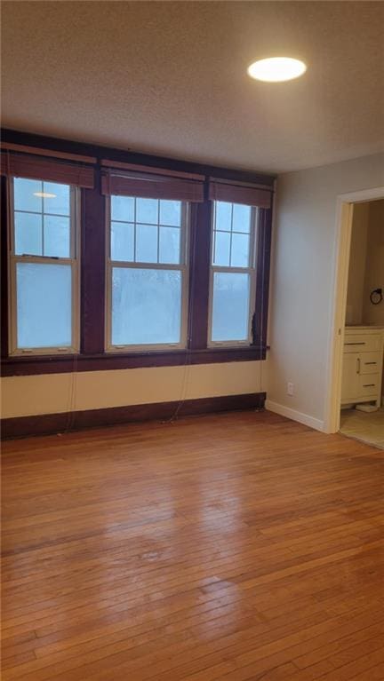 spare room featuring a textured ceiling and light wood-type flooring