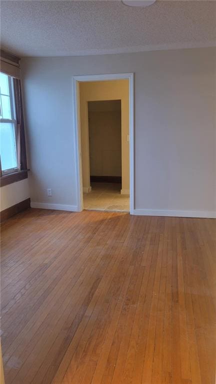 spare room featuring light hardwood / wood-style flooring and a textured ceiling