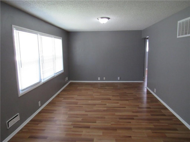 empty room with dark hardwood / wood-style floors and a textured ceiling