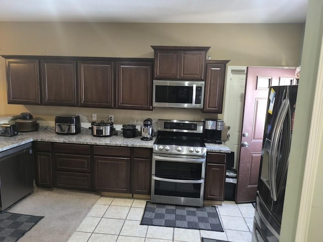 kitchen with appliances with stainless steel finishes, dark brown cabinets, and light tile patterned floors