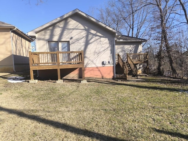 rear view of property featuring a wooden deck and a lawn