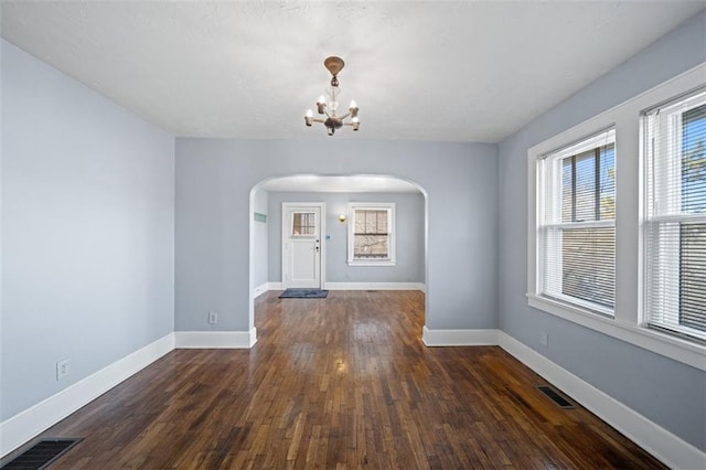 entryway featuring baseboards, visible vents, arched walkways, dark wood finished floors, and a notable chandelier