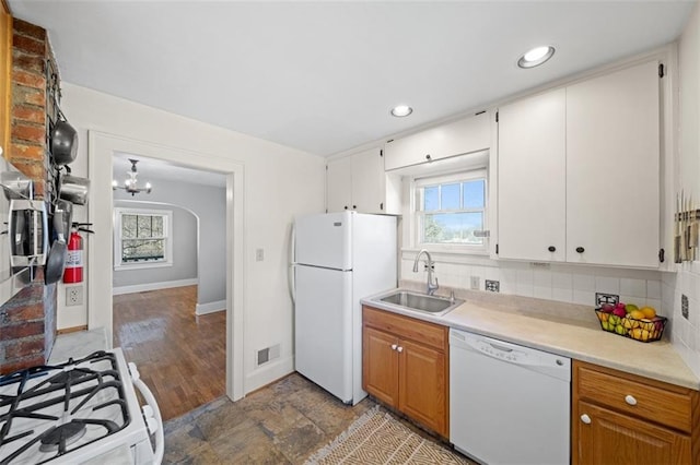 kitchen with white appliances, brown cabinetry, light countertops, white cabinetry, and a sink