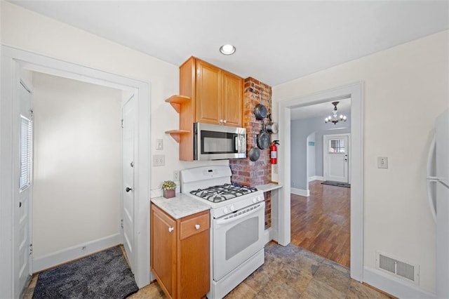 kitchen with arched walkways, white appliances, visible vents, light countertops, and open shelves